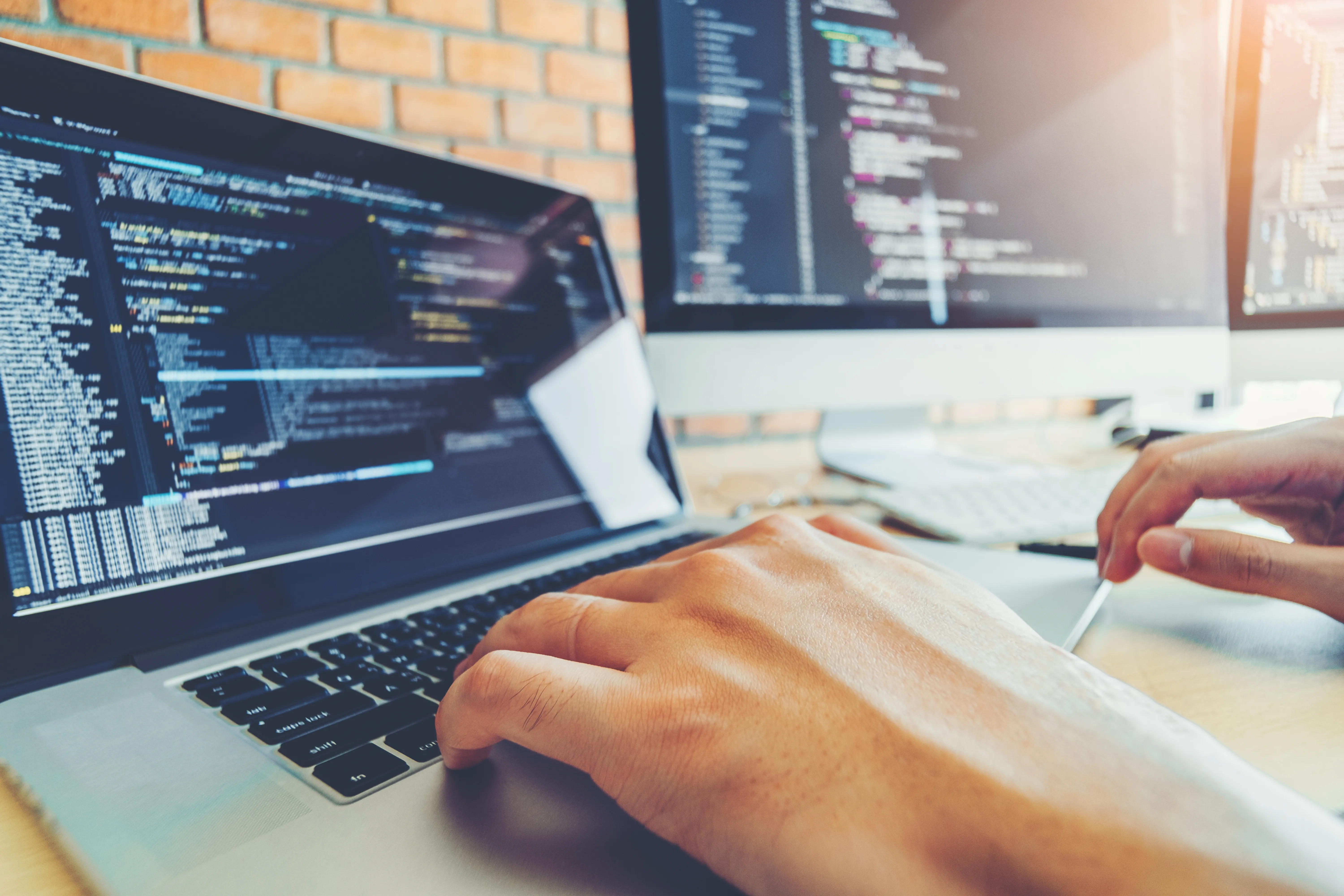 Code-editor op een laptop met een tweede monitor met code