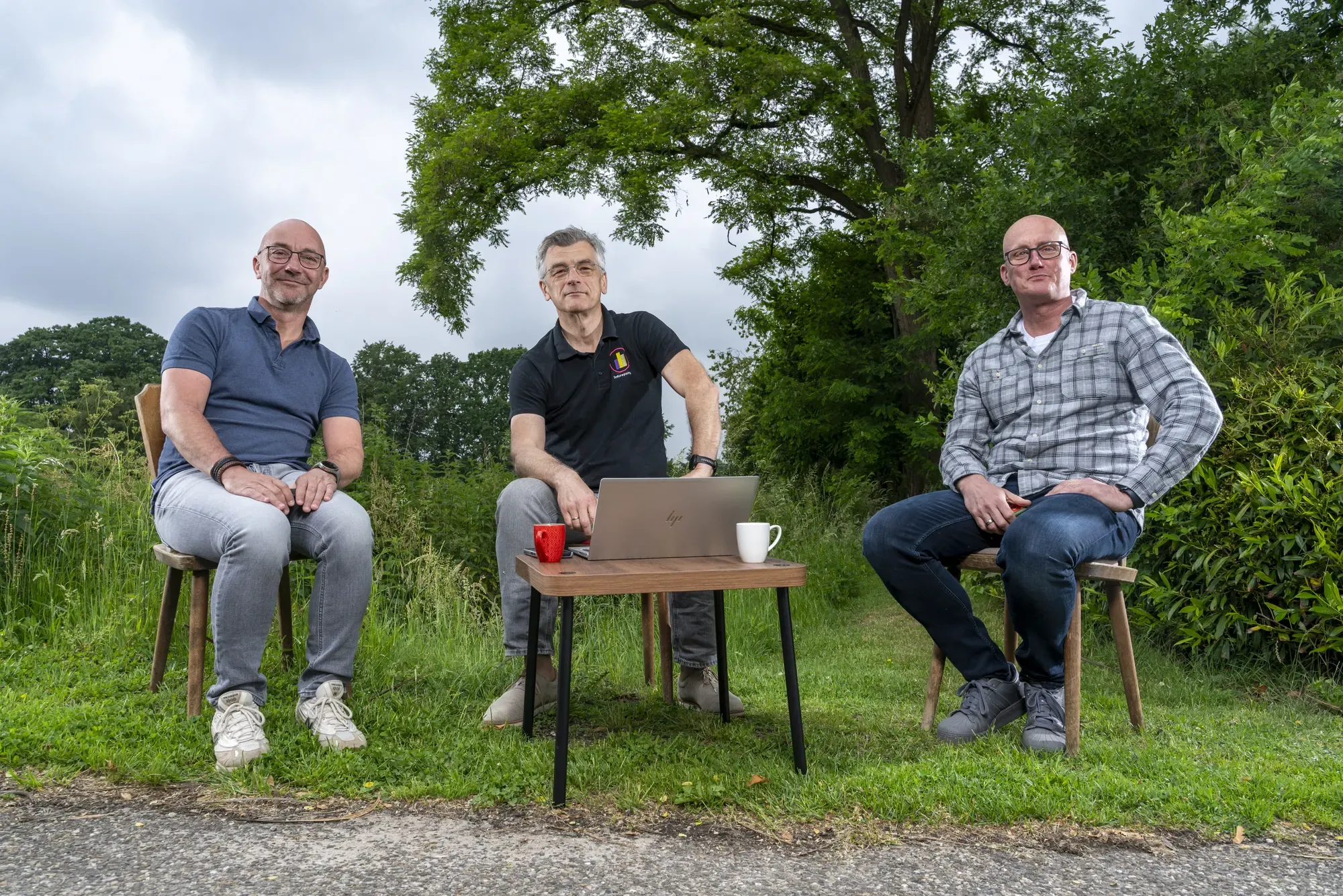 Drie collega’s van InfoReports zitten buiten rond een laptop