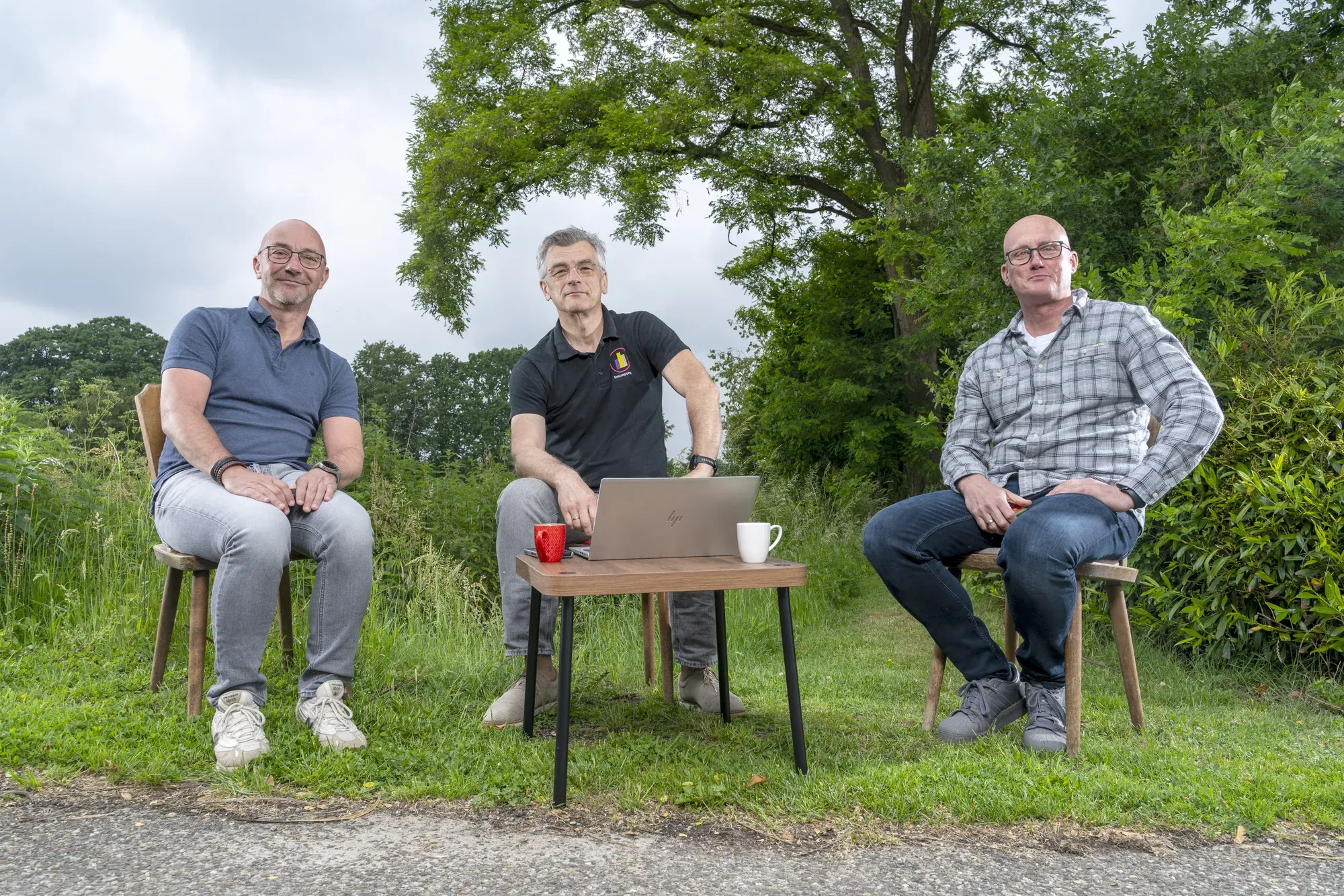 Drie collega’s van InfoReports zitten buiten rond een laptop